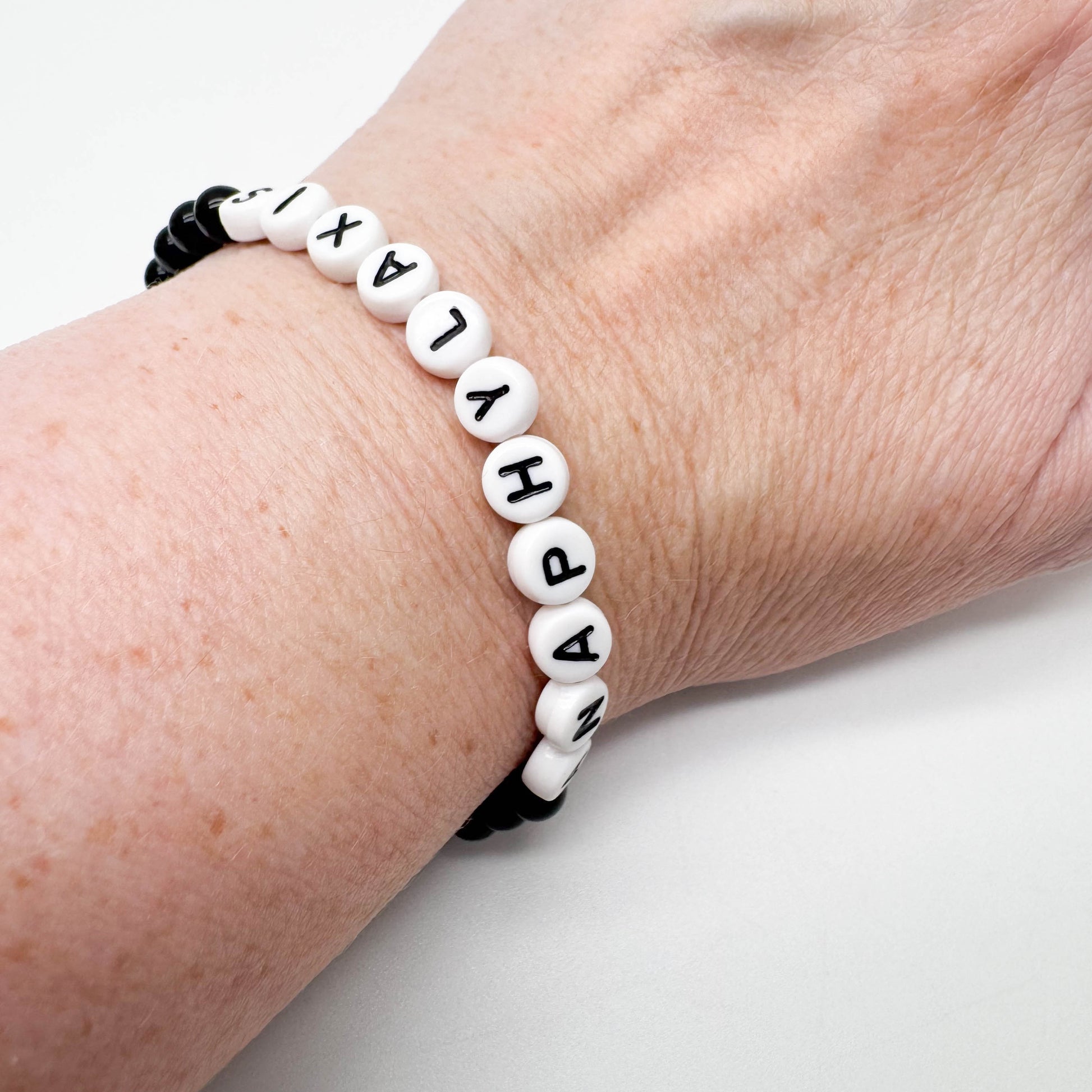 A bracelet made of beads with the word "HAPPY" spelled out in black letters.
