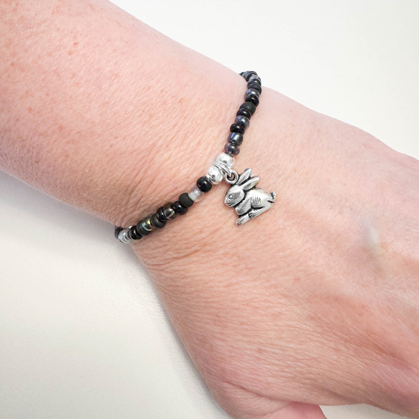 A bracelet with black beads and a silver charm featuring a rabbit.