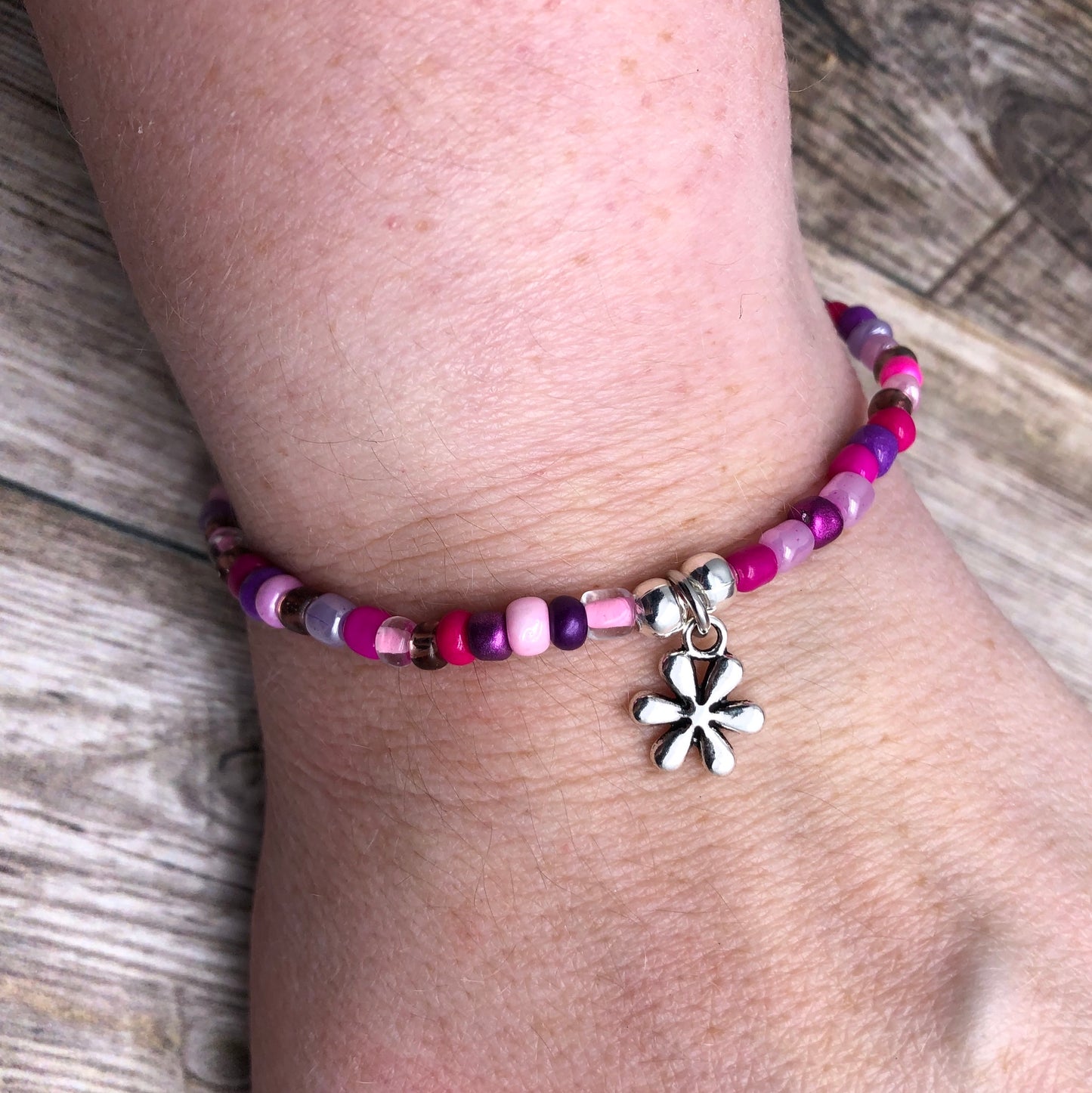 A bracelet made of colorful beads and a charm on a person's wrist.