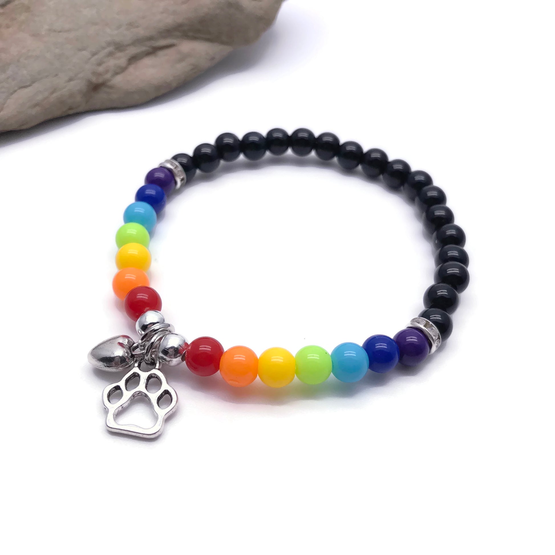 Rainbow bridge bracelet laying flat next to stone